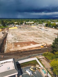 An overhead view of a leveled construction site. The ground is mostly dirt with some concrete footings spaced throughout the site.