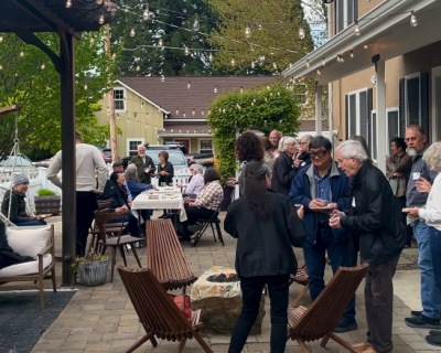 A group of people mingle on a patio near a hotel