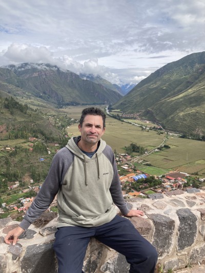 Robb sits on a stone wall overlooking a green valley