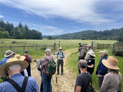 A group of people gather outside on open ranch land