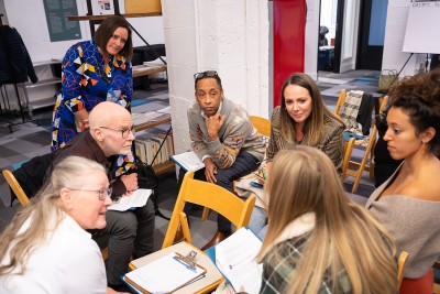 A group on people sits in a close circle in a meeting room and discusses something