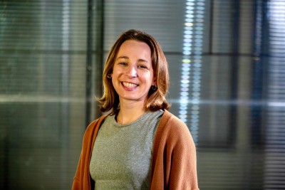 Anna stands against a glass wall and smiles
