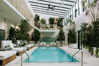 An indoor pool surrounded by plants and wide, striped chaises.