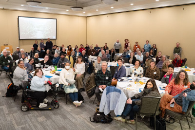 A large group of people gathered in an indoor setting, smiling for the camera