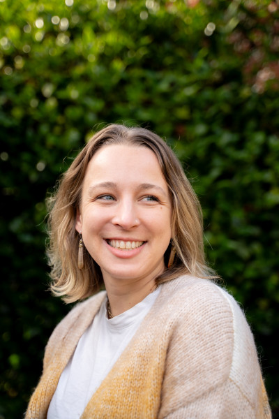 A smiling woman with short, sandy-blond hair and a tan cardigan
