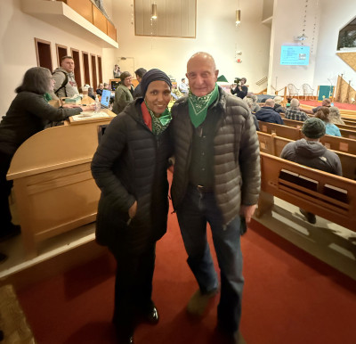 A woman and a man pose together for a photo at the back of a crowded church