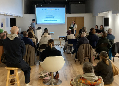 Two people presenting in front of a full room of people