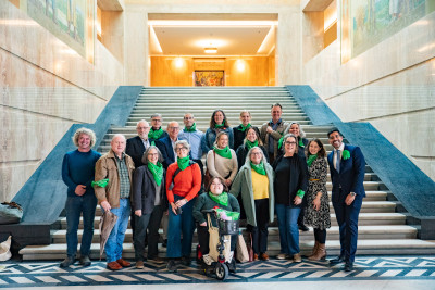 A smiling group of people wearing green bandanas in the state capitol