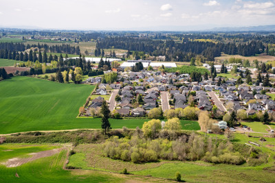 Aerial view of a densely built town, surrounded by agricultural fields and forests