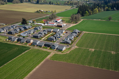 Aerial view of homes surrounded on all sides by farmland and forest