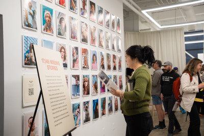 A woman reading a pamphlet and looking at a wall of artwork