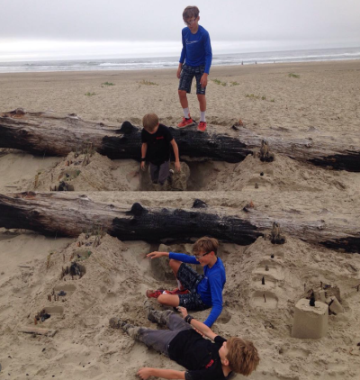 Two photos, one on top of the other, showing two boys playing in a hole in the sand next to a log, with distant surf and an overcast sky.