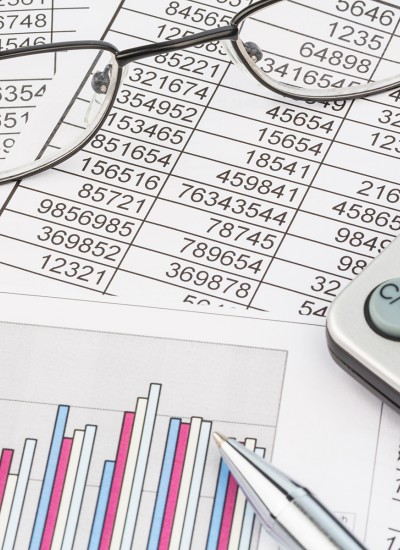 A photo of spreadsheets, graphs, a calculator, and glasses