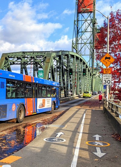 A TriMet bus crosses a bridge, with pedestrian and bike lanes on the shoulder