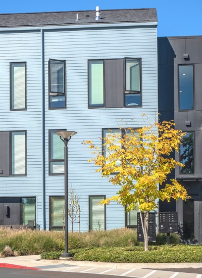 A blue multi-unit residential building with landscaping