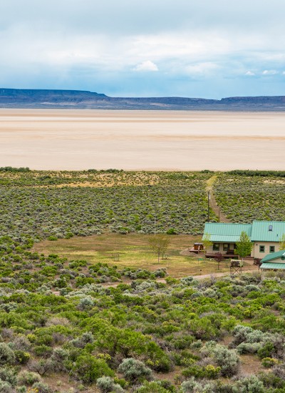 House with cleared space around perimiter abuts the Alvord Desert
