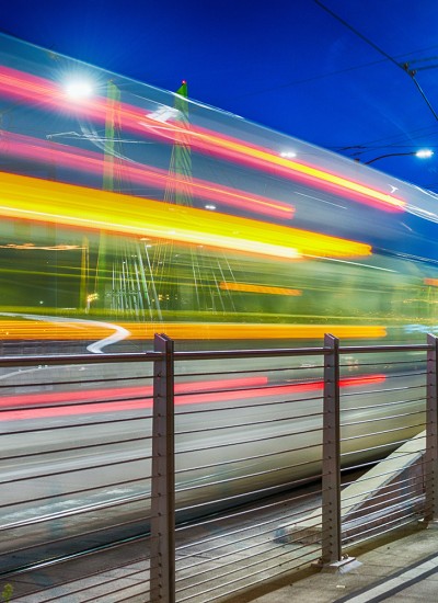 A transit rail car speeds past at night