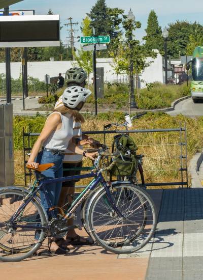 People wait for a bus while standing next to their bikes