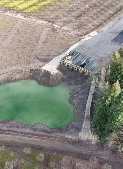 Liquid of an unnatural green fills the pit that sits next to actively farmed orchards