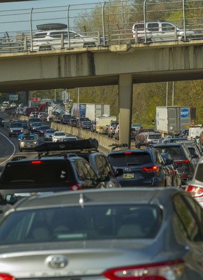 Traffic congestion on an interstate highway has cars lined up bumper to bumper across all lanes.