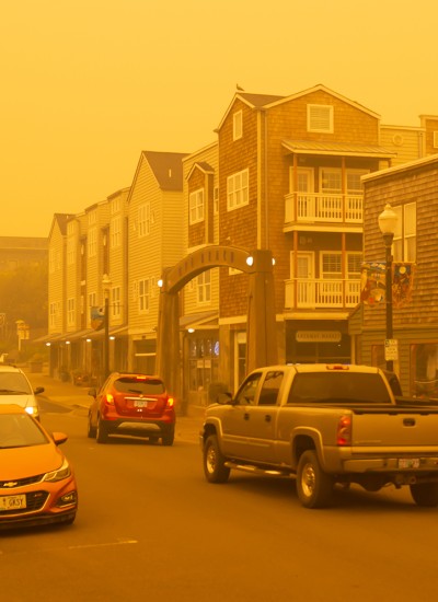 A yellow haze from wildfire smoke hangs over a mixed-use street in Newport
