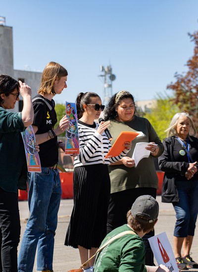 A group of advocates speak at a rally on a sunny day