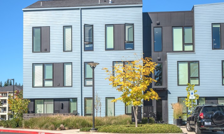 A blue multi-unit residential building with landscaping