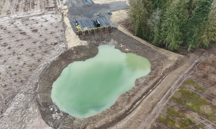 Liquid of an unnatural green fills the pit that sits next to actively farmed orchards