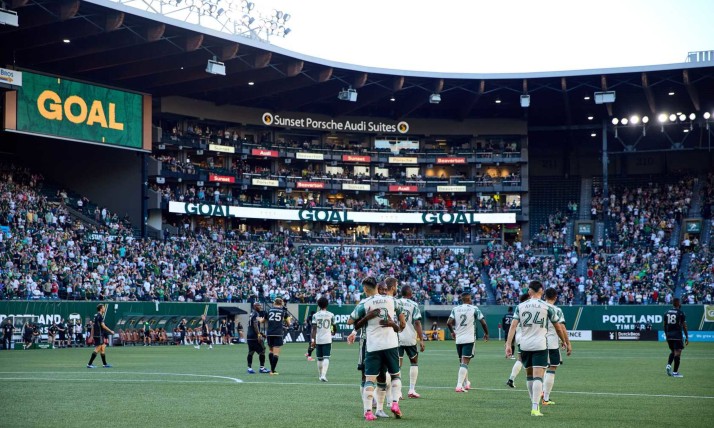 Players on the field at a Timbers match celebrate a goal