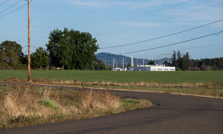 A field abutting an industrial facility shows the contrast of an urban growth boundary