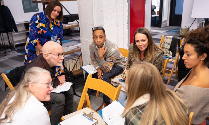 A group on people sits in a close circle in a meeting room and discusses something