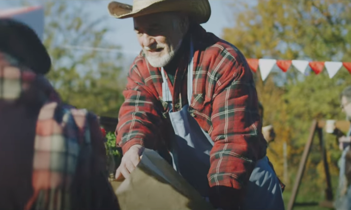 An AI-generated image shows a male farmer helping bag produce at a farmers' market