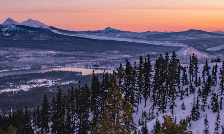 Snowy, mountainous landscape at sunset.