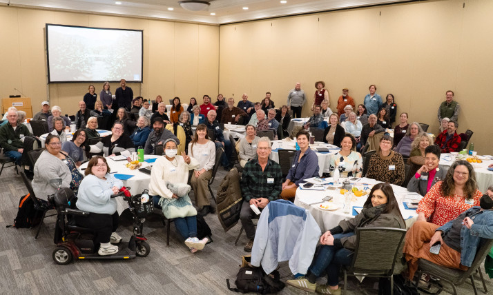 A large group of people gathered in an indoor setting, smiling for the camera