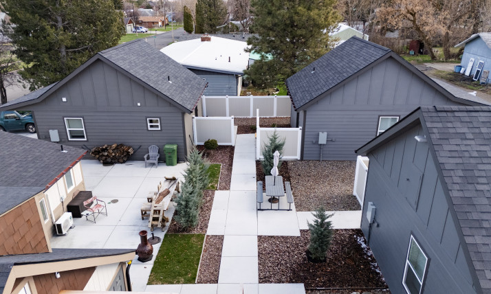 Aerial view of a cottage cluster, several small houses with peaked roofs joined by a central open space and little sidewalks.