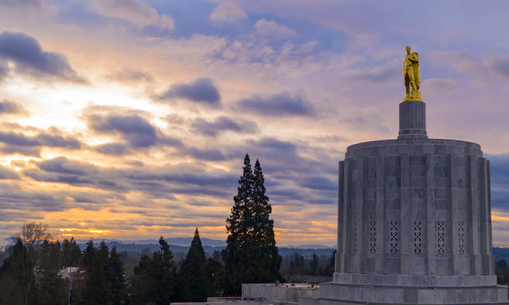 The top of the Oregon state capitol against a sky with pastel sunrise colors