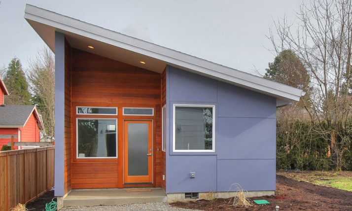 An accessory dwelling unit (ADU), a small home with a sharply angled roof and a combination of pale blue paint and natural-stain wood paneling.