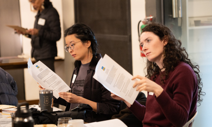 Two women looking at printouts in a group, indoor setting