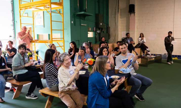 A group of people applauding, while seated at picnic tables