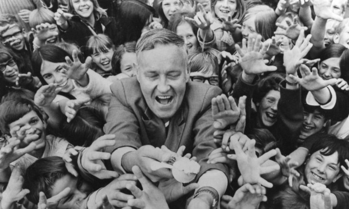 A smiling man in a cheering group of kids