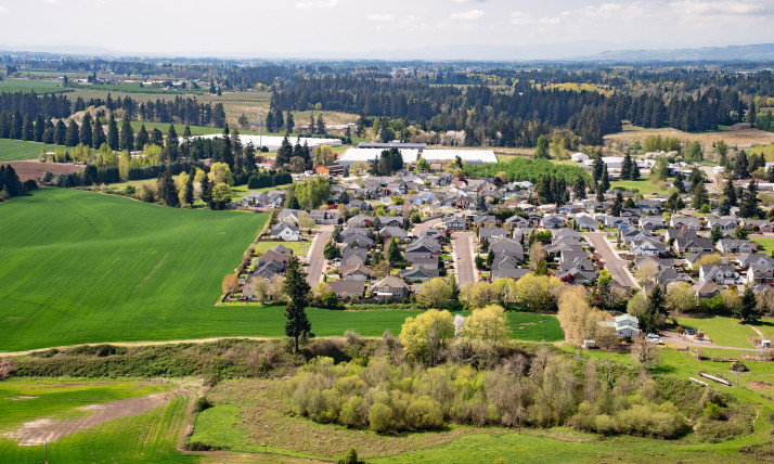 Aerial view of a densely built town, surrounded by agricultural fields and forests