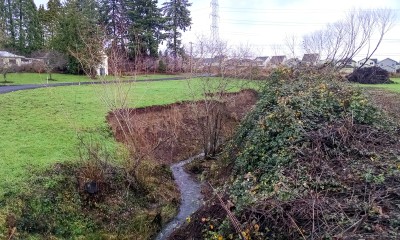 A waterway weaves through open land with houses nearby