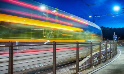 A transit rail car speeds past at night