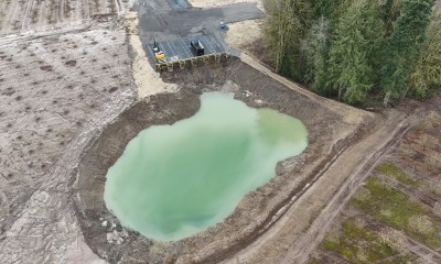 Liquid of an unnatural green fills the pit that sits next to actively farmed orchards