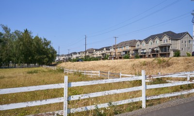 Fenced farmland in the foreground contrasts with a large housing development in the background