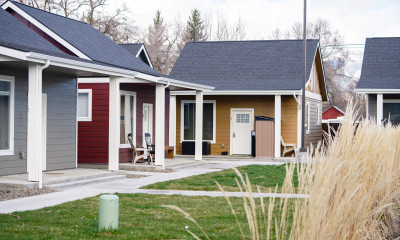 A grouping of small, colorfully painted cottages, all with their front doors facing a central lawn.