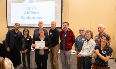 A group of people standing together, around Shelley Wetherell, who is holding a certificate