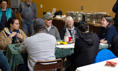 A group of people gathered around a table, deep in conversation, in an indoor setting