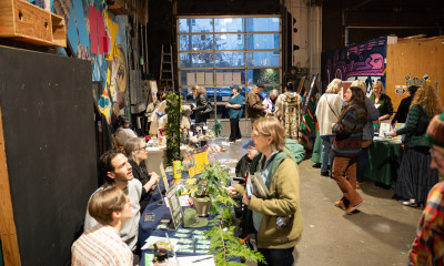 A crowded, colorful indoor setting with many booths being visited by people