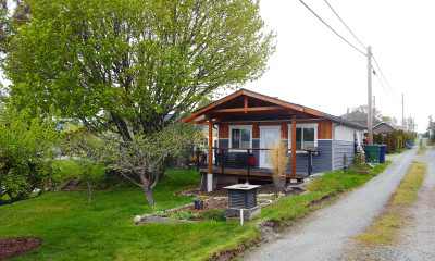 An accessory dwelling unit along a pastoral alleyway, with trees and a small garden.